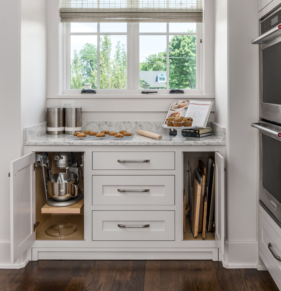 Example of a transitional l-shaped dark wood floor and brown floor open concept kitchen design in Nashville with an undermount sink, beaded inset cabinets, white cabinets, quartz countertops, white backsplash, stone tile backsplash, stainless steel appliances, an island and white countertops