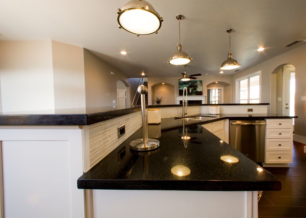 Example of a transitional porcelain tile eat-in kitchen design in Austin with an undermount sink, shaker cabinets, white cabinets, granite countertops, white backsplash, glass sheet backsplash, stainless steel appliances and an island