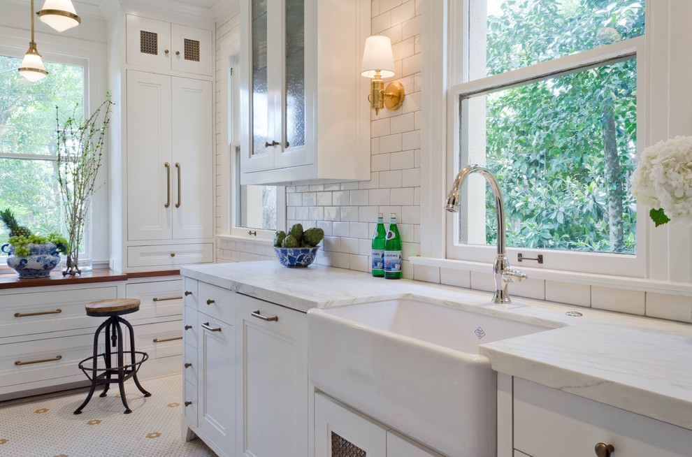Design ideas for a small traditional galley separate kitchen in Austin with a farmhouse sink, recessed-panel cabinets, white cabinets, marble benchtops, white splashback, subway tile splashback, panelled appliances, no island and porcelain floors.