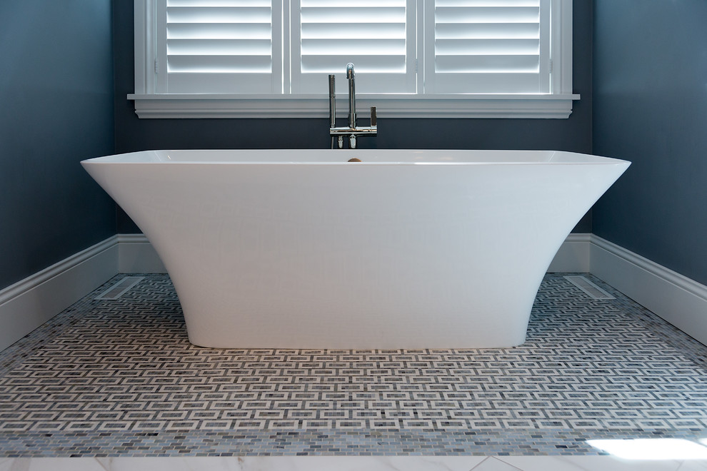 Inspiration for a large transitional master gray tile and stone tile marble floor freestanding bathtub remodel with recessed-panel cabinets, white cabinets, gray walls, a vessel sink and marble countertops