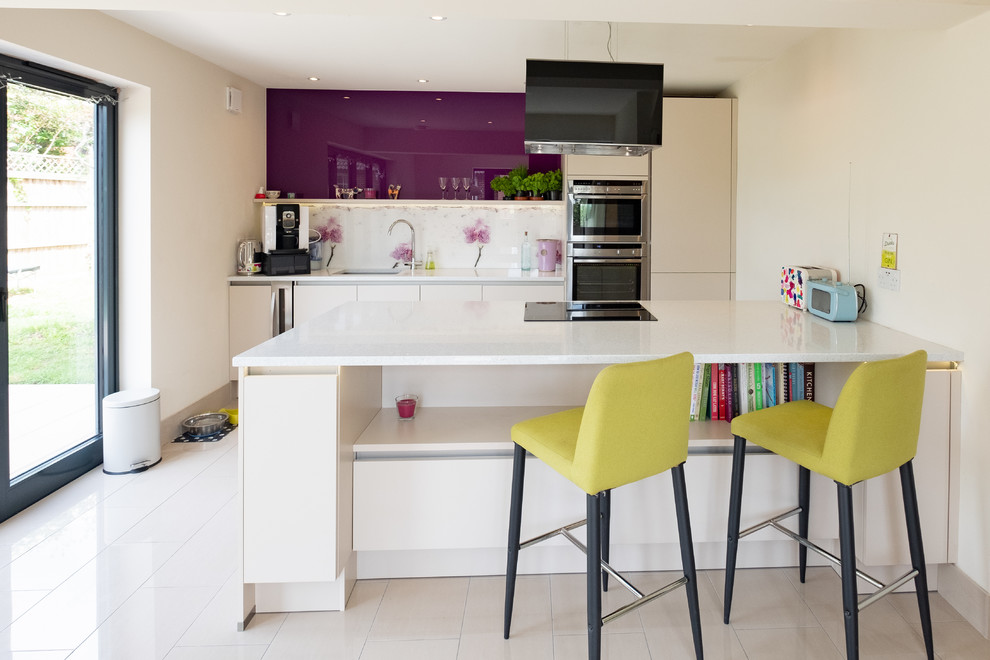 Design ideas for a mid-sized contemporary single-wall kitchen in Wiltshire with an undermount sink, flat-panel cabinets, white cabinets, quartzite benchtops, white splashback, stainless steel appliances, with island, white floor and white benchtop.