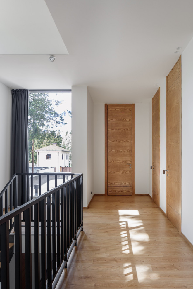 Источник вдохновения для домашнего уюта: коридор среднего размера: освещение в современном стиле с белыми стенами, паркетным полом среднего тона и коричневым полом