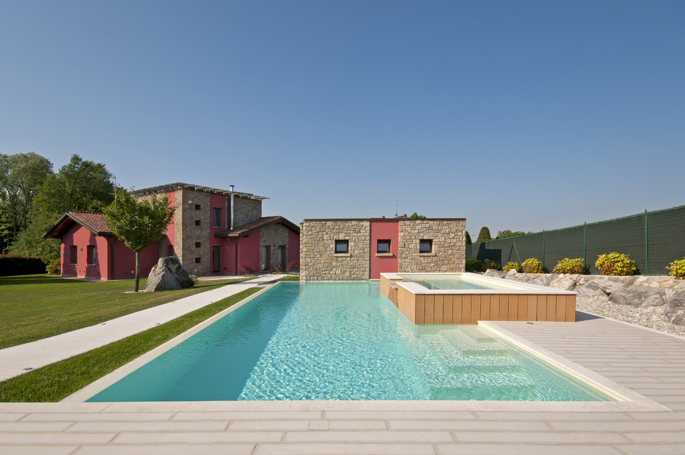 Photo of a large country backyard rectangular pool in Milan with a hot tub.