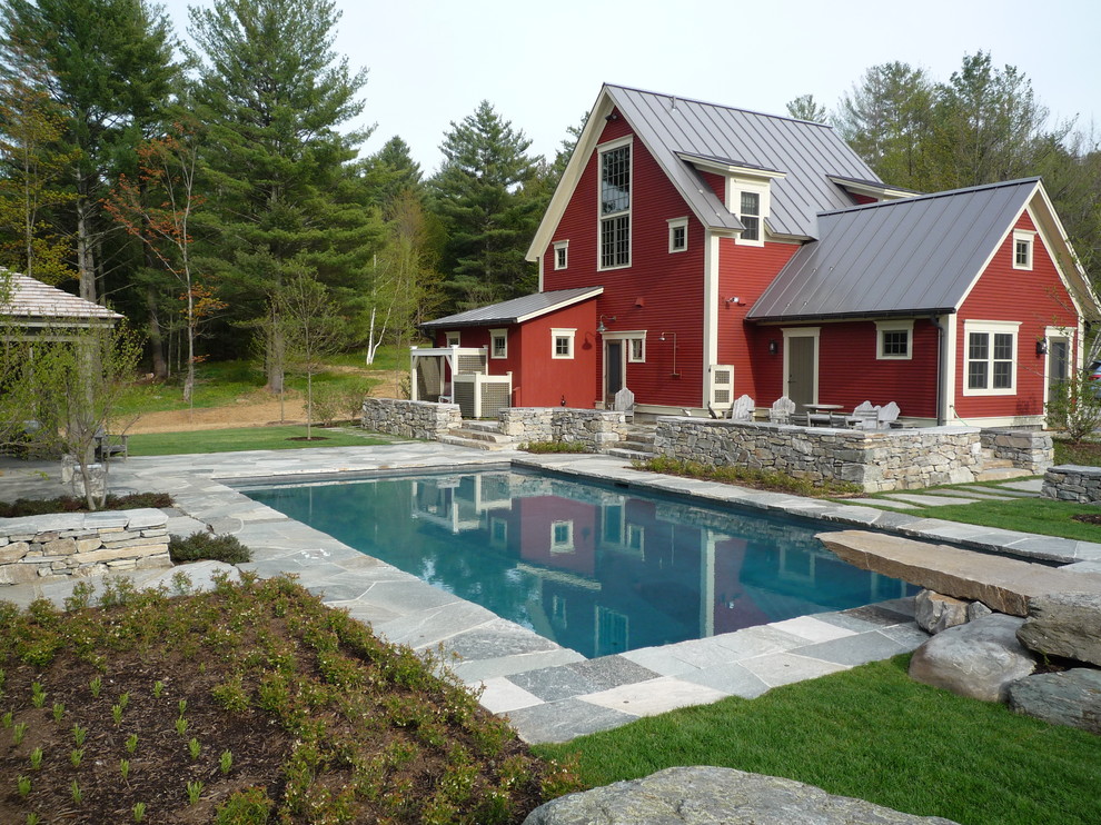 This is an example of a large traditional backyard rectangular pool in Burlington with natural stone pavers.