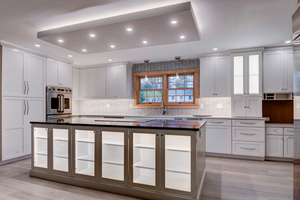 Open concept kitchen - large transitional u-shaped light wood floor and beige floor open concept kitchen idea in New York with an undermount sink, shaker cabinets, white cabinets, quartzite countertops, white backsplash, ceramic backsplash, stainless steel appliances, an island and white countertops
