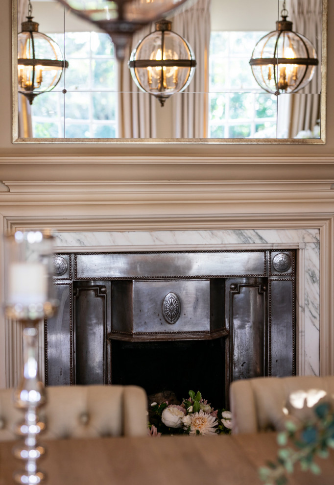 Inspiration for a large traditional separate dining room in Surrey with beige walls, light hardwood floors, a standard fireplace, a metal fireplace surround, brown floor and panelled walls.