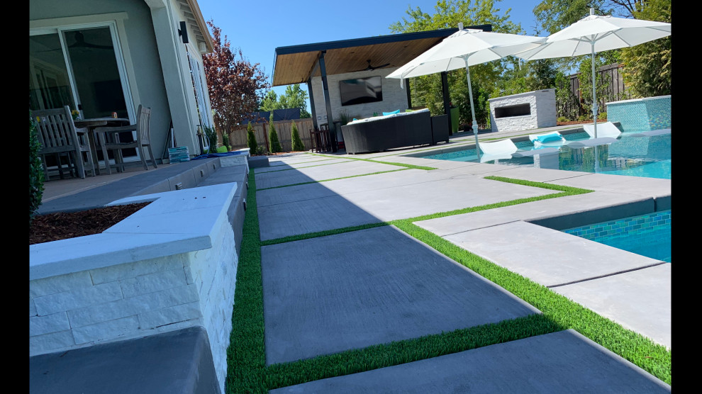 Стильный дизайн: прямоугольный ландшафтный бассейн среднего размера на заднем дворе в стиле неоклассика (современная классика) с покрытием из бетонных плит - последний тренд