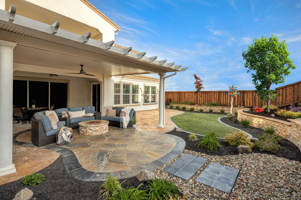 Immagine di un grande patio o portico boho chic dietro casa con pavimentazioni in pietra naturale e un tetto a sbalzo