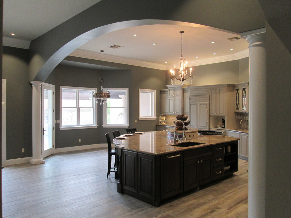 Inspiration for a huge transitional l-shaped porcelain tile open concept kitchen remodel in Phoenix with an undermount sink, raised-panel cabinets, gray cabinets, granite countertops, gray backsplash, stone tile backsplash, stainless steel appliances and an island