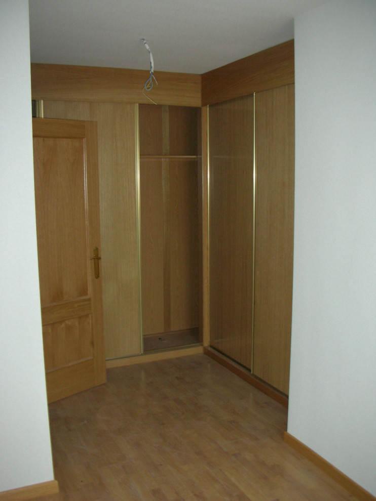 Photo of a large modern gender-neutral storage and wardrobe in Other with recessed-panel cabinets, medium wood cabinets and medium hardwood floors.