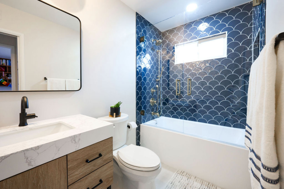 Mid-sized contemporary kids bathroom in San Diego with flat-panel cabinets, brown cabinets, an alcove tub, a shower/bathtub combo, a two-piece toilet, blue tile, porcelain tile, white walls, porcelain floors, an undermount sink, engineered quartz benchtops, grey floor, a hinged shower door, multi-coloured benchtops, a niche, a single vanity and a freestanding vanity.