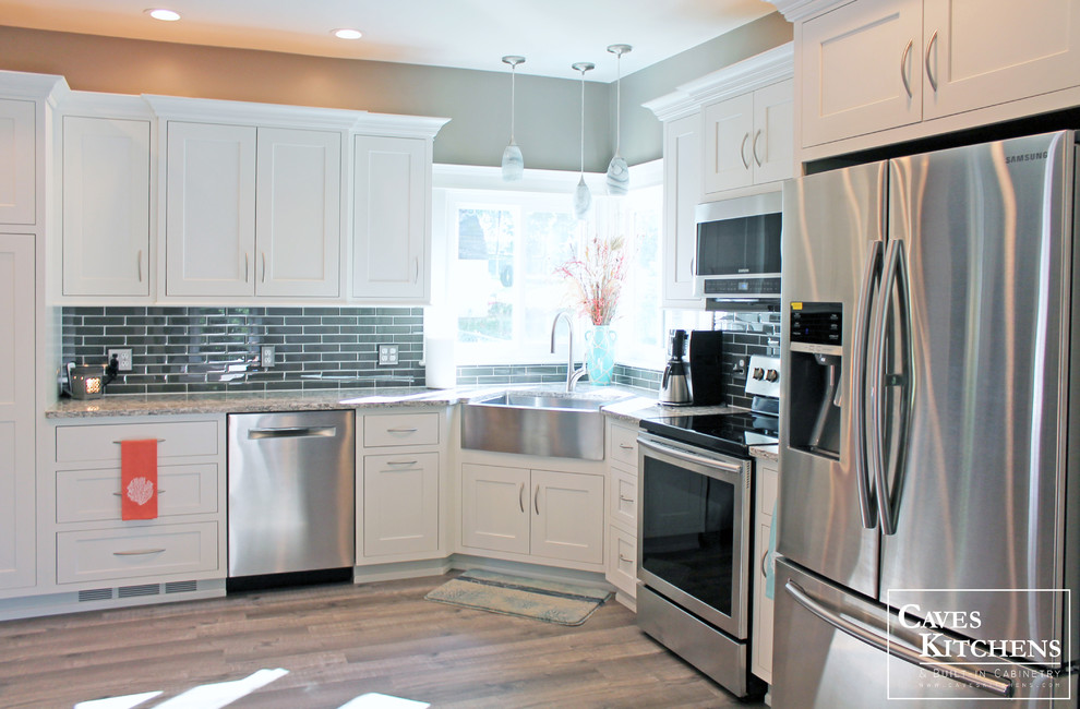 Eat-in kitchen - small transitional l-shaped medium tone wood floor eat-in kitchen idea in New York with a farmhouse sink, recessed-panel cabinets, white cabinets, quartz countertops, black backsplash, subway tile backsplash, stainless steel appliances and no island
