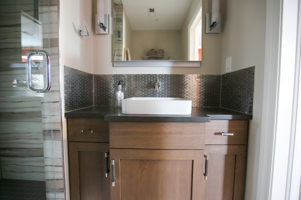 Inspiration for a mid-sized transitional kids bathroom in Indianapolis with black cabinets, a hinged shower door, recessed-panel cabinets, an alcove shower, metal tile, beige walls, a vessel sink, engineered quartz benchtops and black benchtops.