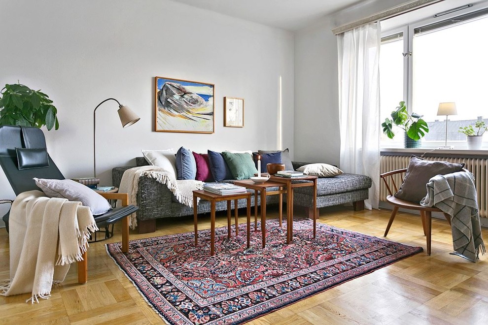 Photo of a mid-sized scandinavian open concept family room in Stockholm with grey walls, light hardwood floors and no tv.