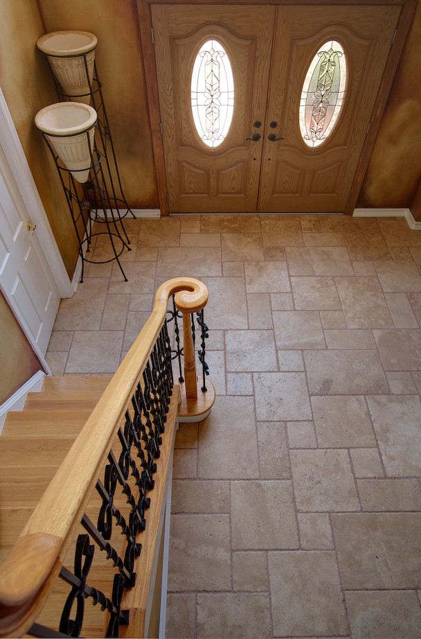Traditional entryway in Other with travertine floors and a medium wood front door.