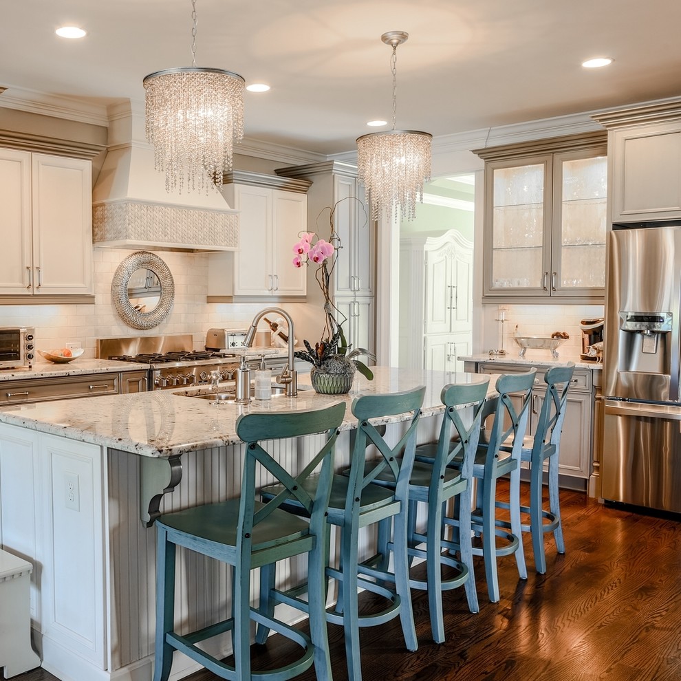 Design ideas for a transitional l-shaped kitchen in Raleigh with an undermount sink, recessed-panel cabinets, white cabinets, white splashback, subway tile splashback, stainless steel appliances, dark hardwood floors, with island, brown floor and grey benchtop.