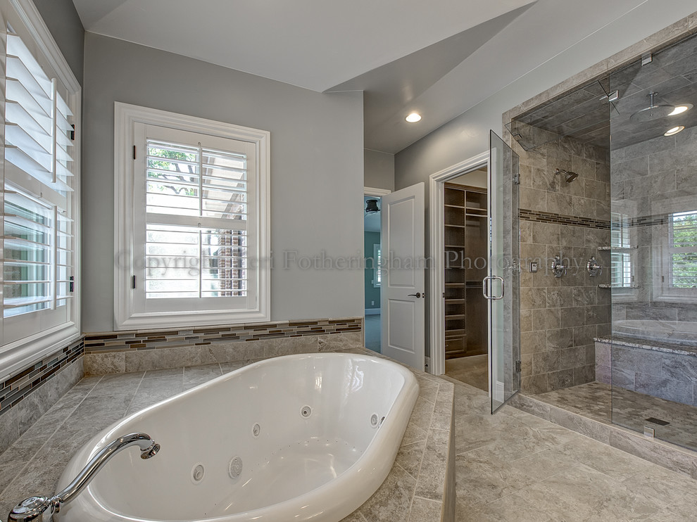 Photo of a transitional master bathroom in Denver with a drop-in tub, a double shower, beige tile and blue walls.