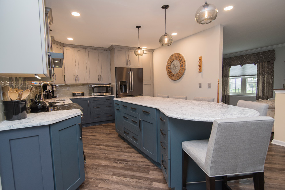 Eat-in kitchen - mid-sized transitional l-shaped brown floor eat-in kitchen idea in Baltimore with a single-bowl sink, shaker cabinets, gray cabinets, quartz countertops, gray backsplash, subway tile backsplash, stainless steel appliances, an island and white countertops
