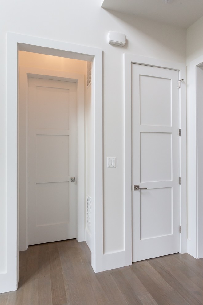 This is an example of a contemporary hallway in DC Metro with white walls, light hardwood floors and grey floor.