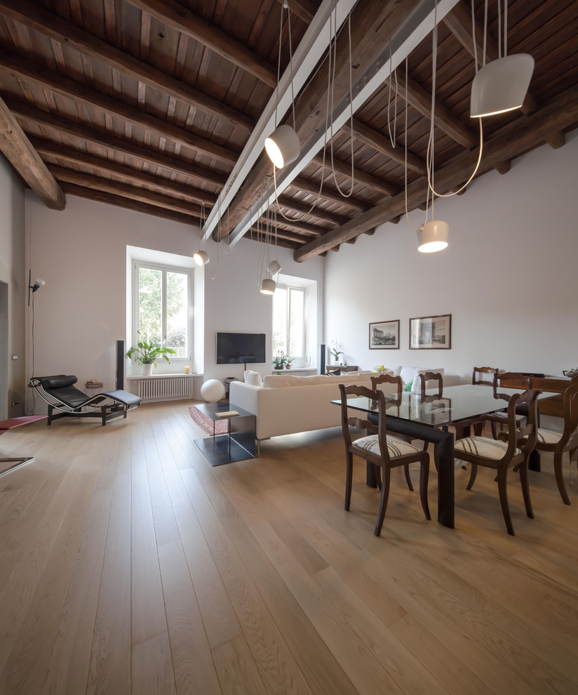 This is an example of an expansive contemporary open concept living room in Rome with white walls, light hardwood floors and a wall-mounted tv.