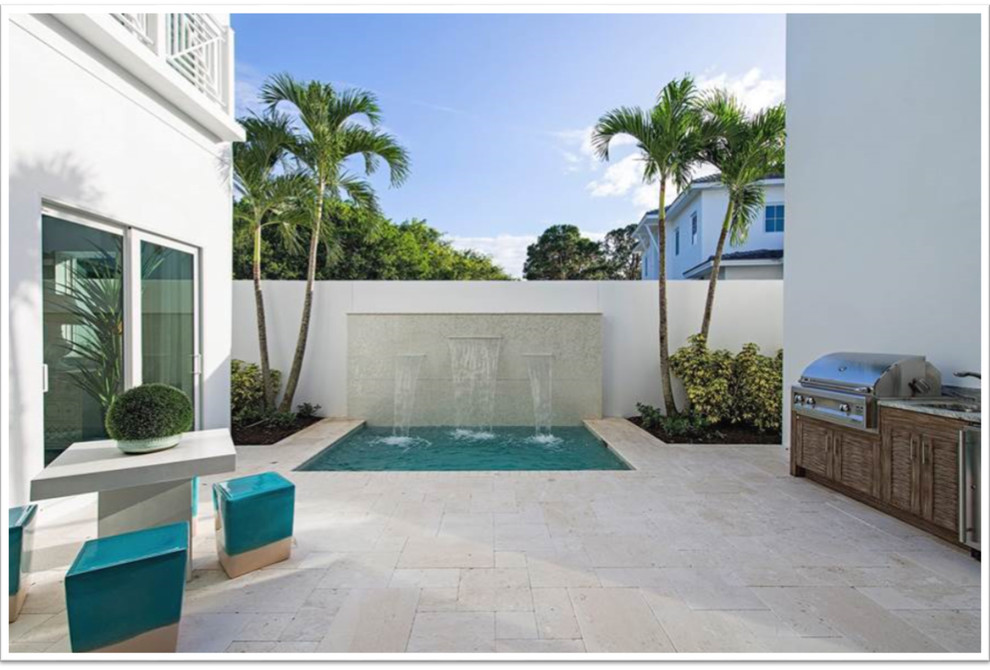 This is an example of a small beach style courtyard rectangular natural pool in Miami with a water feature and natural stone pavers.
