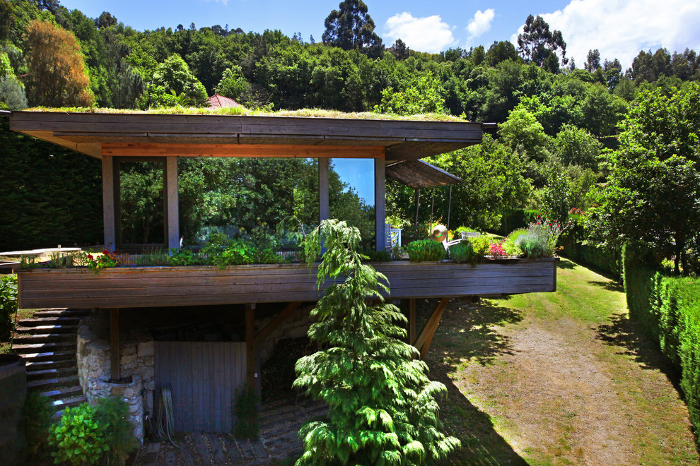 Photo of a small tropical one-storey brown house exterior in Other with wood siding, a flat roof and a green roof.