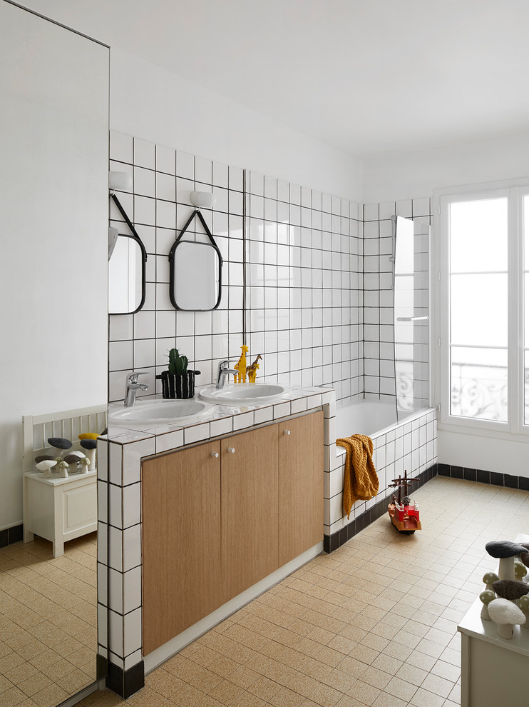 Design ideas for a large contemporary kids bathroom in Paris with flat-panel cabinets, white tile, porcelain tile, white walls, cement tiles, tile benchtops, white benchtops, medium wood cabinets, an alcove tub, a shower/bathtub combo, a drop-in sink and beige floor.