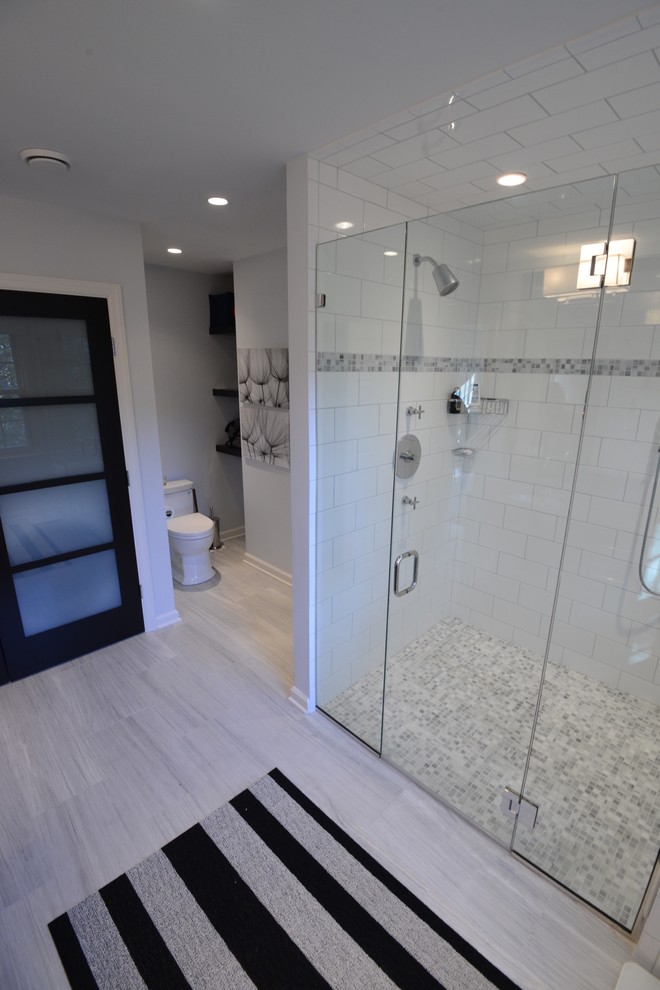 This is an example of a large contemporary master bathroom in New York with an undermount sink, furniture-like cabinets, dark wood cabinets, limestone benchtops, a curbless shower, a one-piece toilet, white tile, stone tile, grey walls and marble floors.