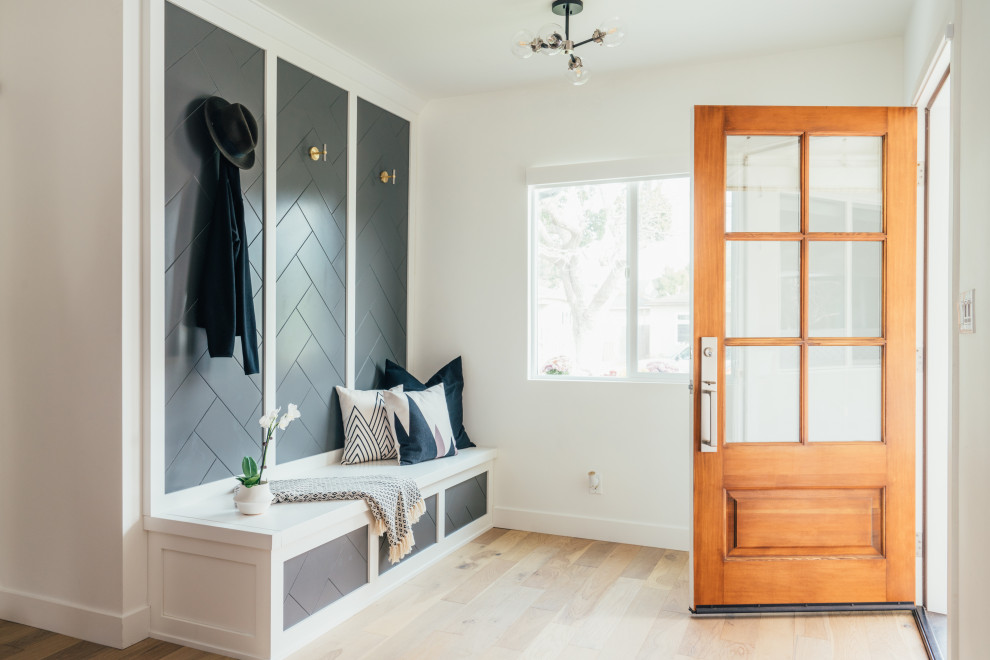 This is an example of a transitional mudroom in Los Angeles with white walls, medium hardwood floors, a single front door, a medium wood front door and brown floor.
