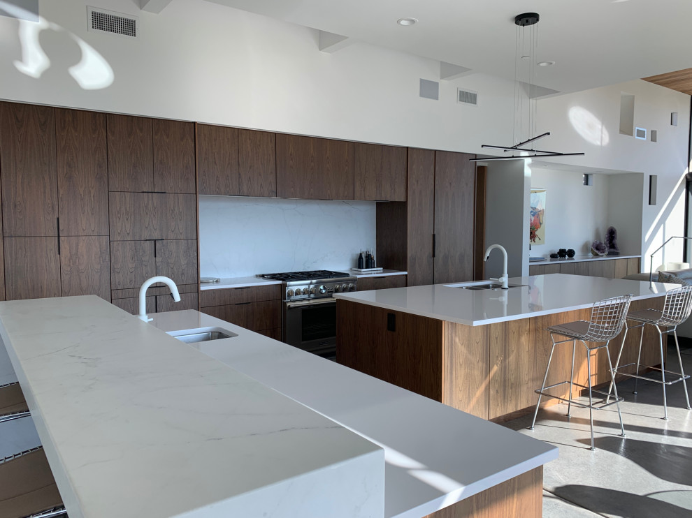 Design ideas for a large modern eat-in kitchen in San Francisco with an undermount sink, flat-panel cabinets, medium wood cabinets, marble benchtops, white splashback, marble splashback, stainless steel appliances, concrete floors, multiple islands, grey floor and white benchtop.