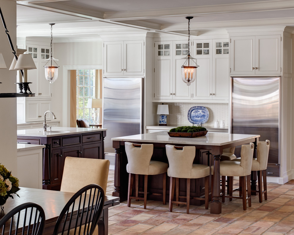 Inspiration for a large traditional u-shaped eat-in kitchen in Charlotte with an undermount sink, white cabinets, quartzite benchtops, white splashback, stainless steel appliances, terra-cotta floors, multiple islands, recessed-panel cabinets, matchstick tile splashback and beige floor.