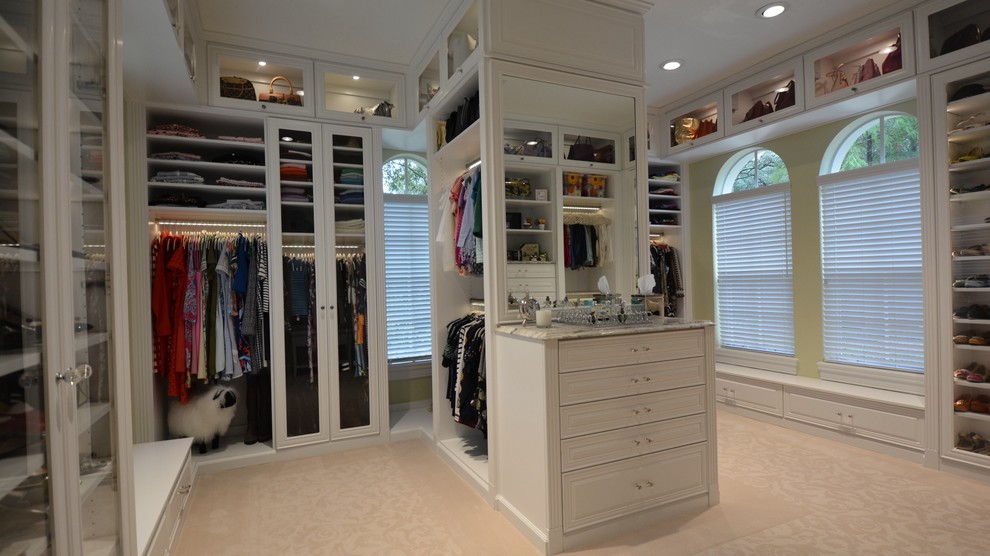 Photo of a large transitional women's walk-in wardrobe in Orange County with glass-front cabinets, white cabinets and carpet.