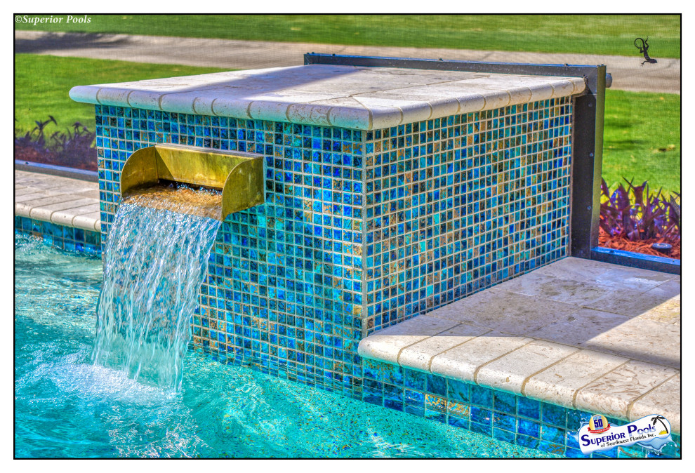 Mid-sized traditional backyard rectangular pool in Tampa with a water feature and natural stone pavers.