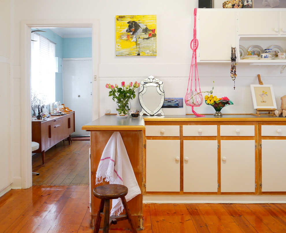 This is an example of a small eclectic eat-in kitchen in Melbourne with flat-panel cabinets, white cabinets, white splashback and medium hardwood floors.