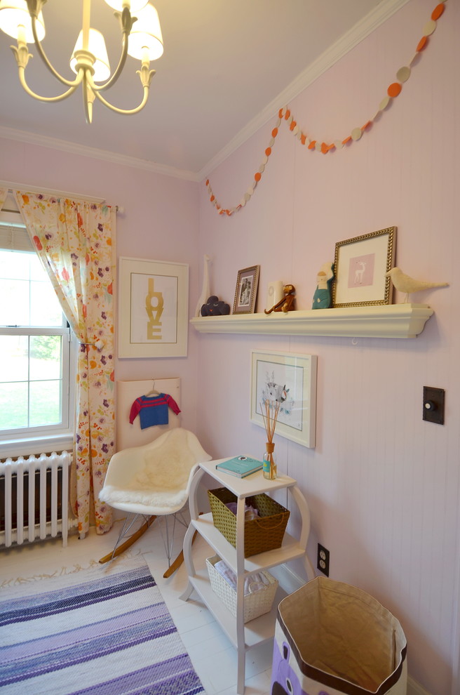 Photo of a traditional nursery for girls in New York with pink walls and painted wood floors.
