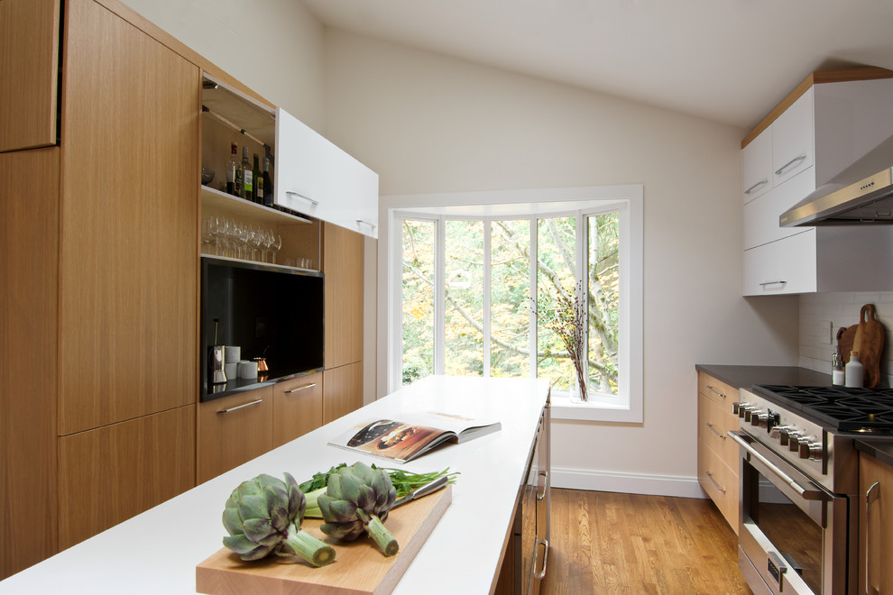 Inspiration for a small modern separate kitchen in Seattle with a single-bowl sink, flat-panel cabinets, light wood cabinets, quartz benchtops, white splashback, ceramic splashback, stainless steel appliances, light hardwood floors and with island.