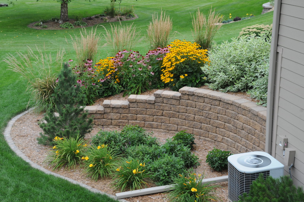 Photo of a large traditional backyard partial sun garden in Minneapolis with a retaining wall.