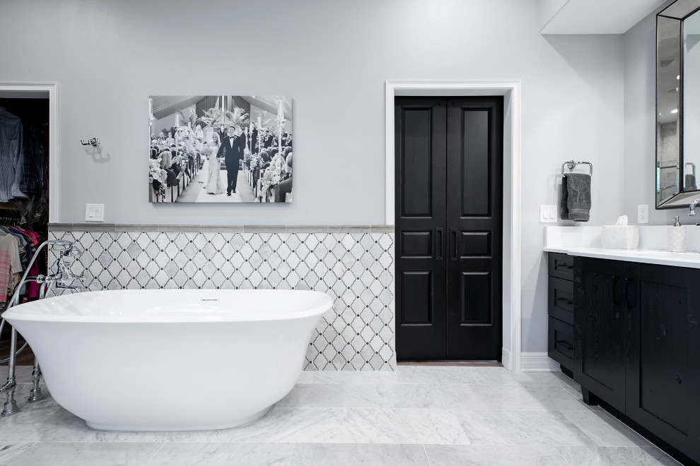 Photo of an expansive traditional master bathroom in Tampa with shaker cabinets, black cabinets, a freestanding tub, an alcove shower, a two-piece toilet, white tile, marble, grey walls, marble floors, an undermount sink, engineered quartz benchtops, white floor, a sliding shower screen and white benchtops.