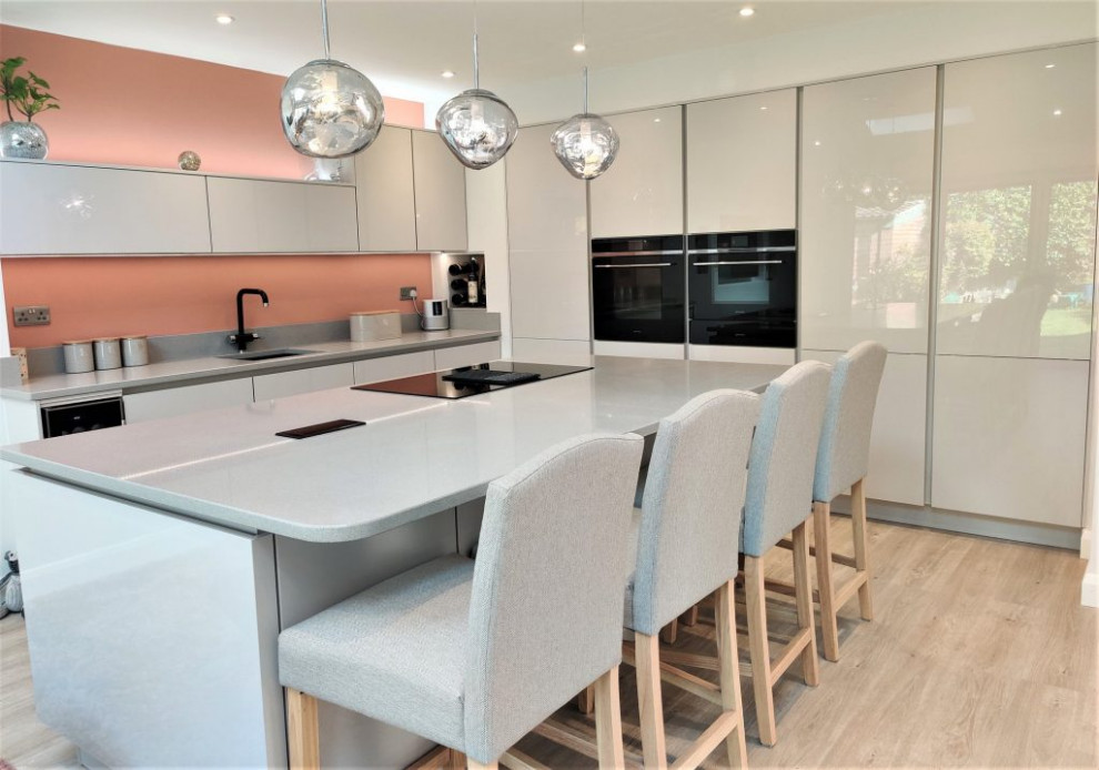Идея дизайна: кухня-гостиная среднего размера: освещение в стиле модернизм с накладной мойкой, серыми фасадами, розовым фартуком, цветной техникой, островом и серой столешницей