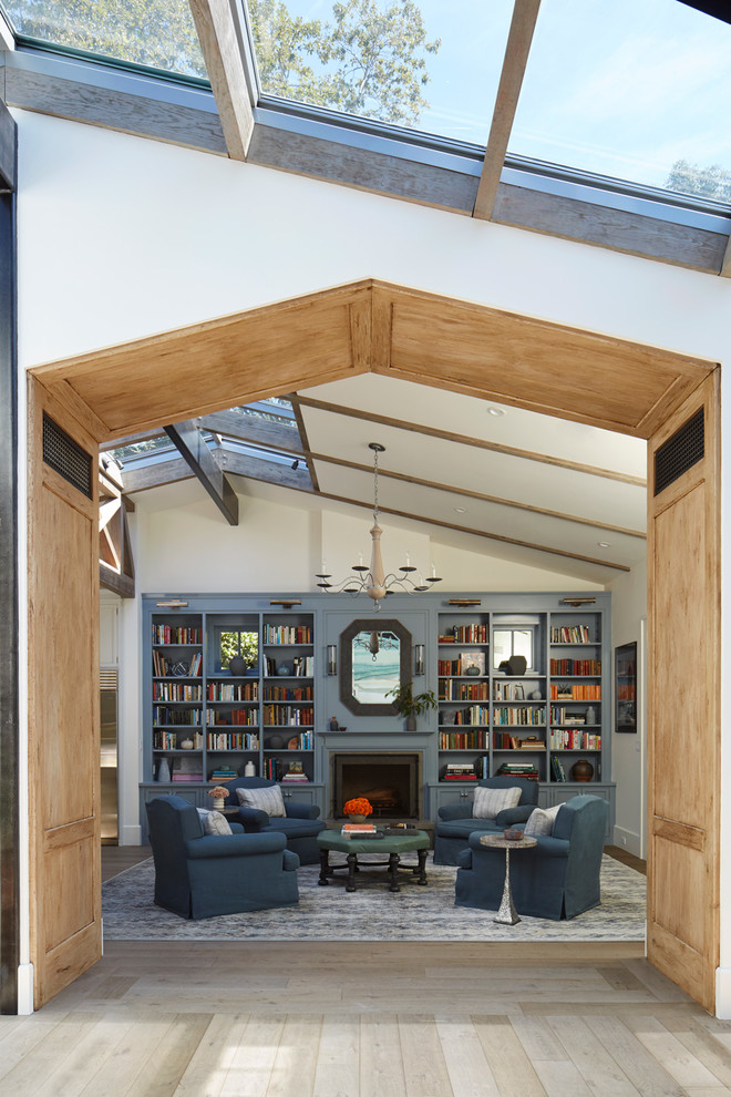 Inspiration for a large beach style living room in Los Angeles with a library, white walls, light hardwood floors, a standard fireplace, no tv and beige floor.