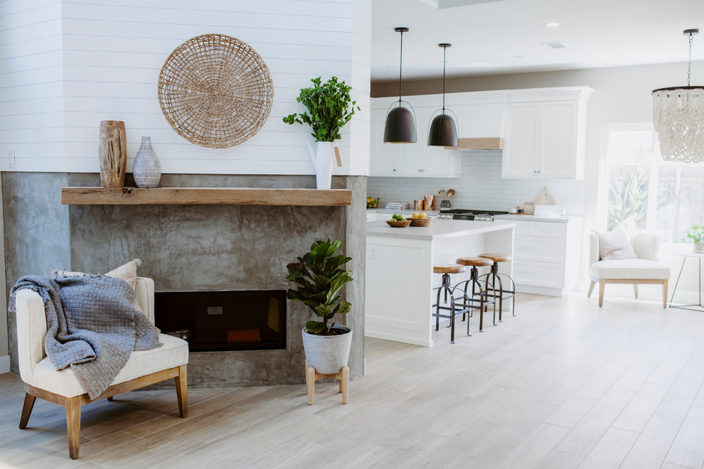 Mid-sized beach style l-shaped open plan kitchen in San Diego with an undermount sink, shaker cabinets, white cabinets, quartz benchtops, white splashback, ceramic splashback, stainless steel appliances, ceramic floors, with island and brown floor.