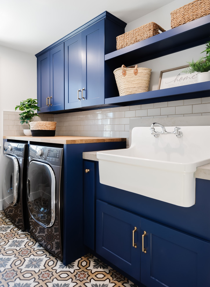 Einzeilige, Kleine Klassische Waschküche mit Landhausspüle, Schrankfronten im Shaker-Stil, blauen Schränken, Arbeitsplatte aus Holz, Küchenrückwand in Grau, Porzellan-Bodenfliesen und Waschmaschine und Trockner nebeneinander in San Diego