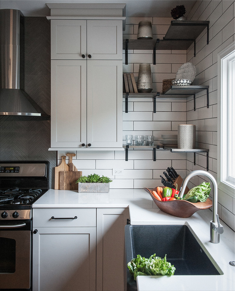 Design ideas for a mid-sized industrial u-shaped eat-in kitchen in Chicago with a farmhouse sink, shaker cabinets, grey cabinets, quartz benchtops, white splashback, ceramic splashback, stainless steel appliances, light hardwood floors, with island, beige floor and grey benchtop.