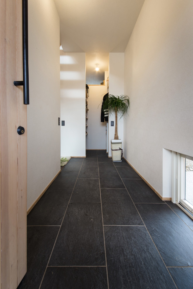 Idee per un corridoio con pareti bianche, una porta singola, una porta in legno chiaro, pavimento nero, soffitto in carta da parati e carta da parati