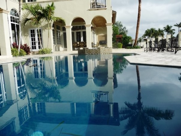 This is an example of a large traditional backyard custom-shaped natural pool in Miami with a hot tub and natural stone pavers.