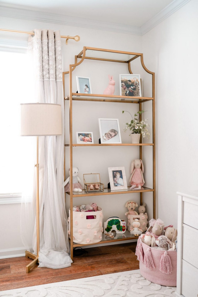 Cette photo montre une chambre de bébé fille tendance de taille moyenne avec un mur blanc, un sol en bois brun, un sol marron et du papier peint.