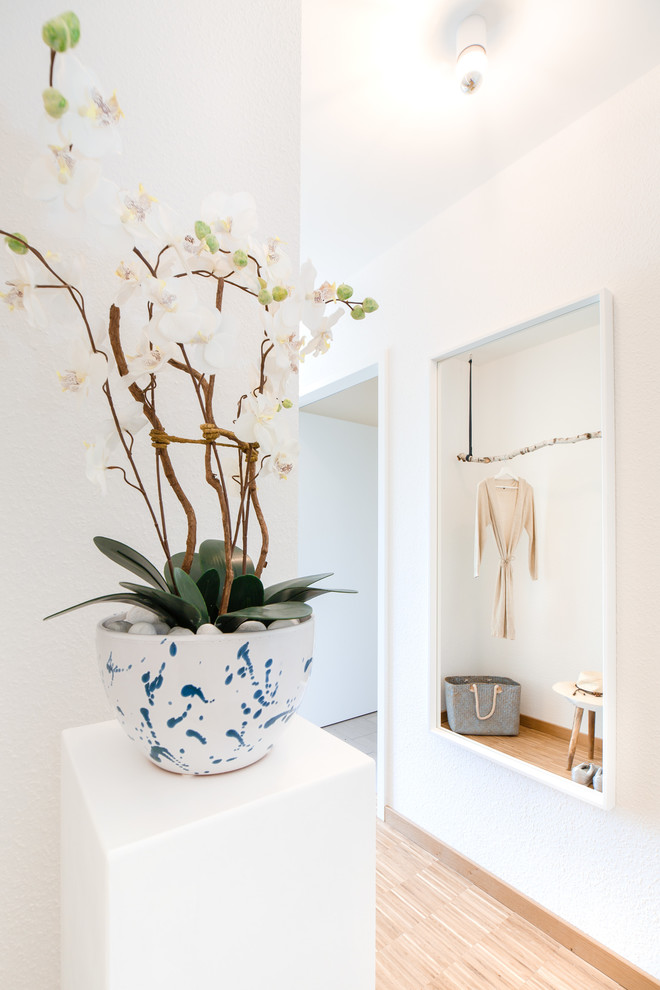 Design ideas for a small scandinavian hallway in Berlin with white walls, bamboo floors and beige floor.