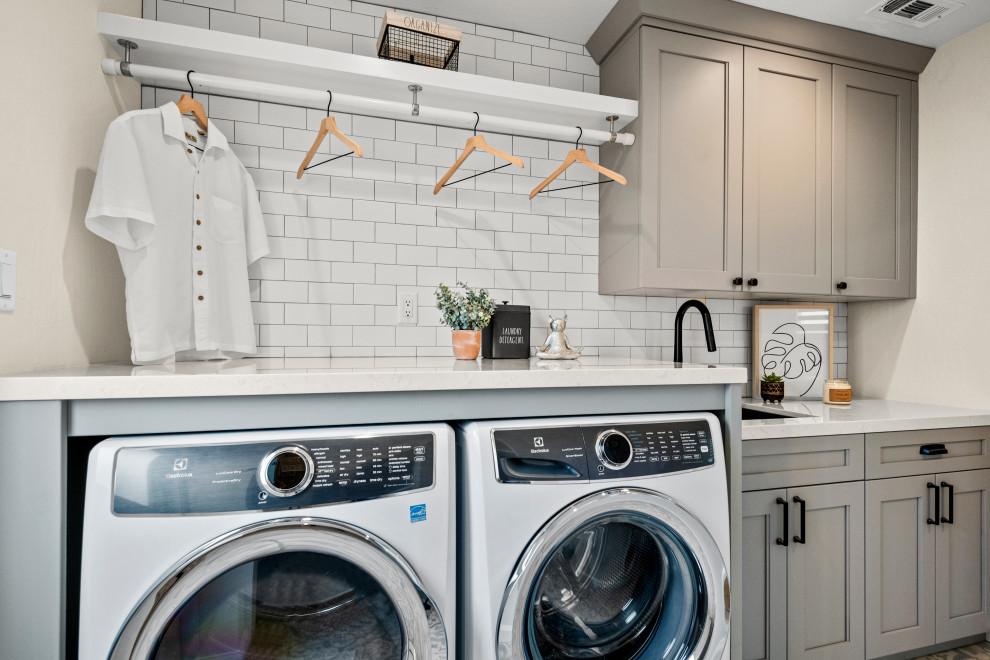 Large arts and crafts galley utility room in San Francisco with an undermount sink, shaker cabinets, grey cabinets, quartzite benchtops, white splashback, subway tile splashback, beige walls, ceramic floors, a side-by-side washer and dryer, multi-coloured floor and white benchtop.
