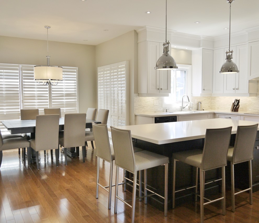 Eat-in kitchen - mid-sized transitional l-shaped medium tone wood floor eat-in kitchen idea in Toronto with an undermount sink, recessed-panel cabinets, white cabinets, quartz countertops, white backsplash, stone tile backsplash, stainless steel appliances and an island