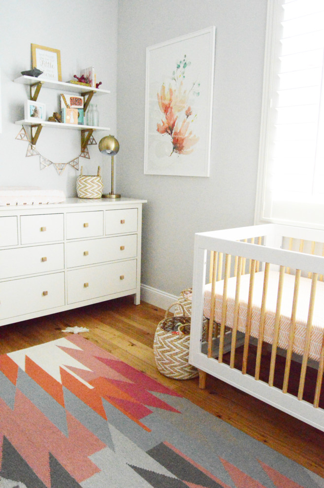 Mid-sized transitional girl medium tone wood floor nursery photo in Orange County with gray walls